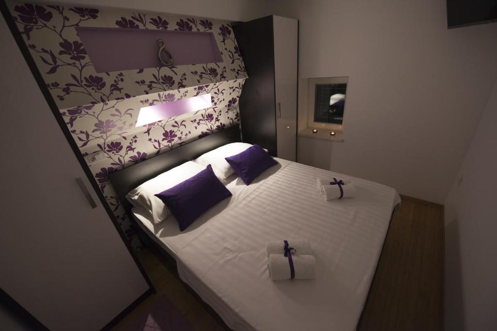 a small bedroom with a bed with purple and white pillows at Apartments Annya in Split