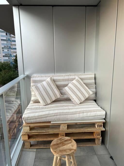 a bench on a balcony with a wooden stool at Chic &amp; moderne appartement - proximité métro in Asnières-sur-Seine