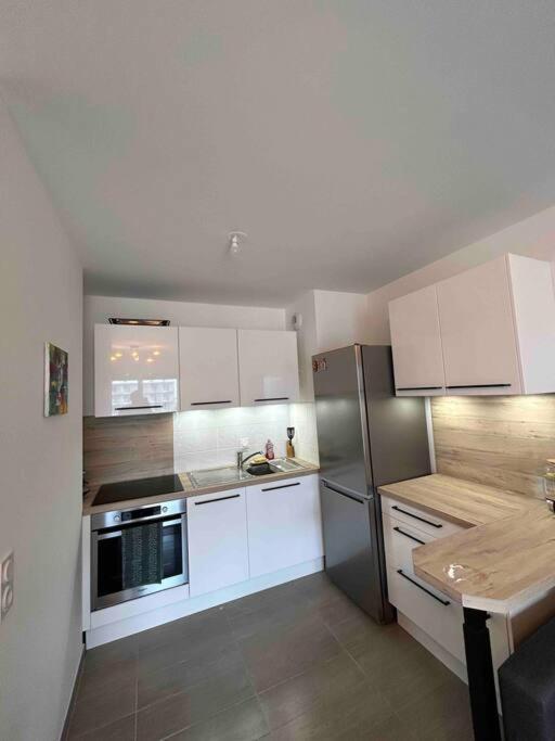 a kitchen with white cabinets and a stainless steel refrigerator at Chic &amp; moderne appartement - proximité métro in Asnières-sur-Seine