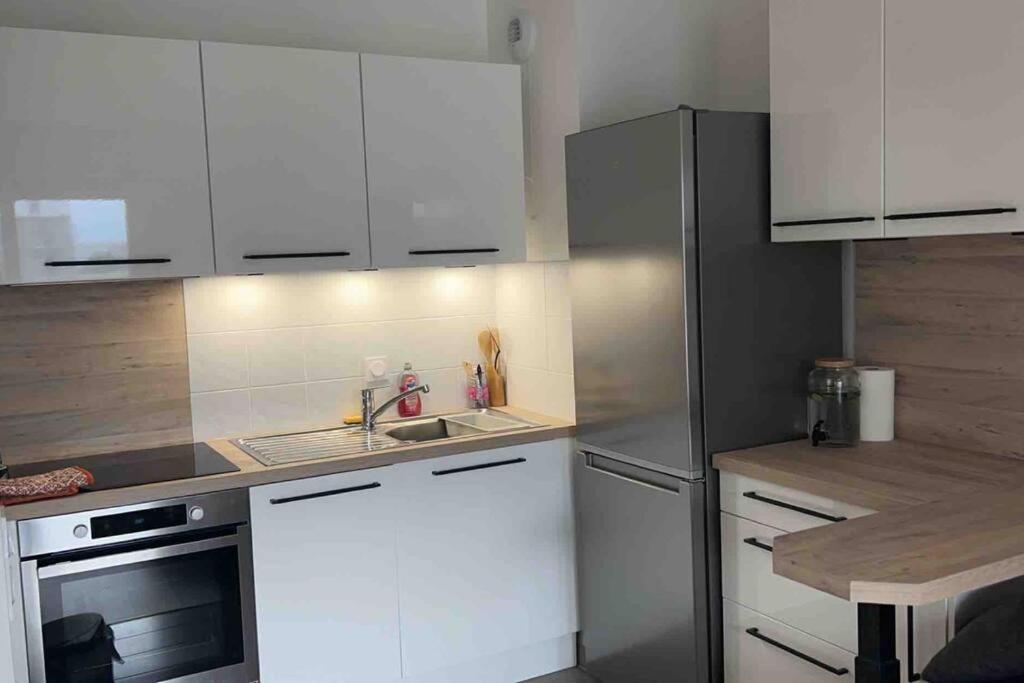 a kitchen with white cabinets and a stainless steel refrigerator at Chic &amp; moderne appartement - proximité métro in Asnières-sur-Seine