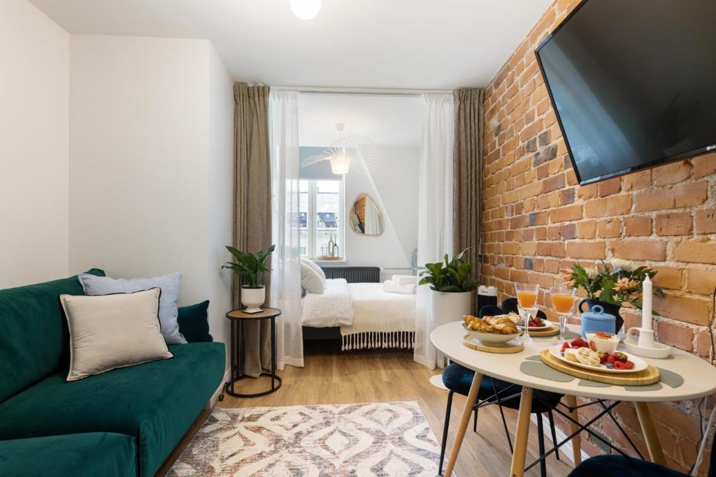 a living room with a green couch and a brick wall at Tempus Te Avangard Tallinn with terrace and gym in Tallinn
