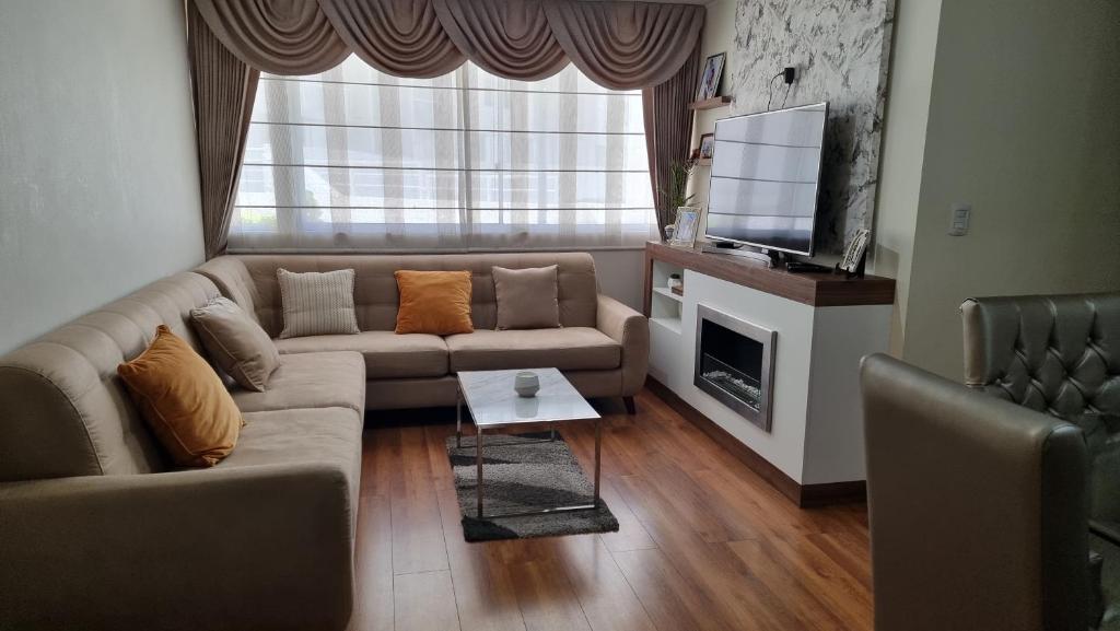 een woonkamer met een bank en een televisie bij Condominio Villa Verde 2 in Arequipa