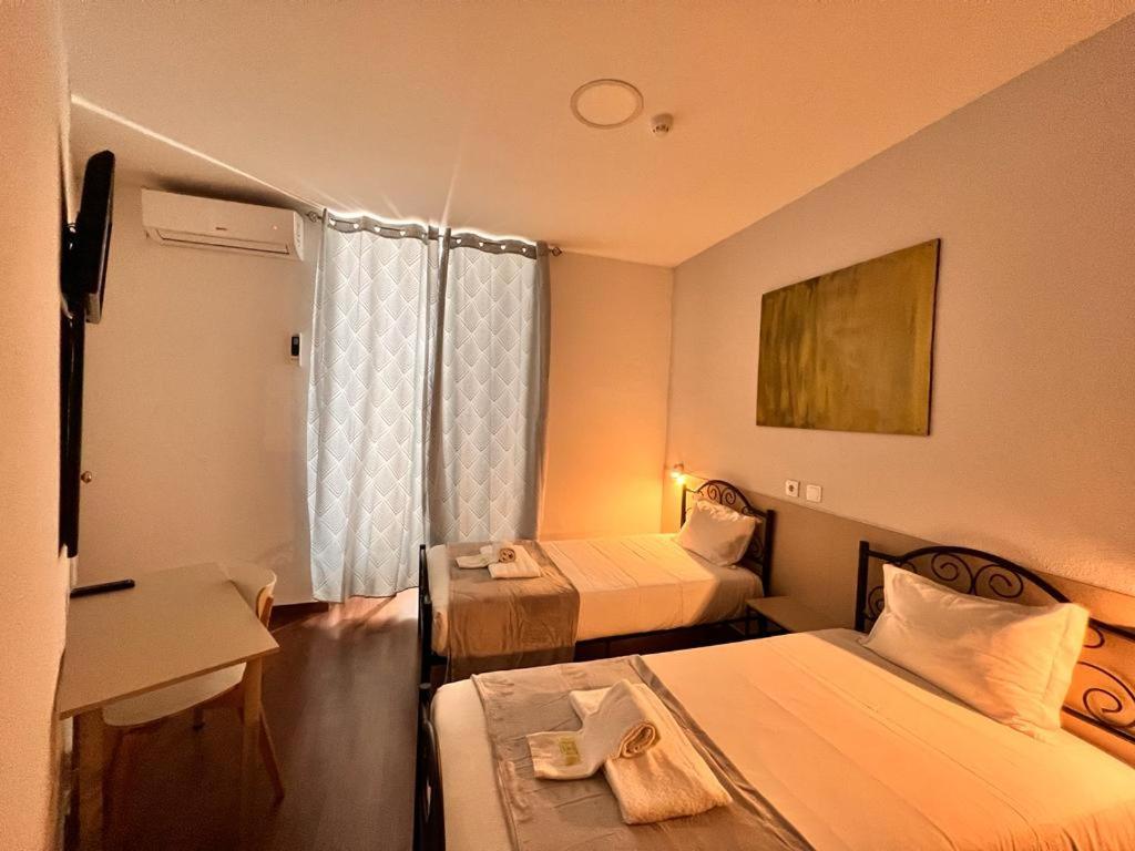 um quarto de hotel com duas camas e uma mesa em Pensao Nova Goa em Lisboa