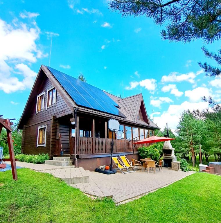 a house with a solar roof and a patio at Sodyba Vilagio in Alanta