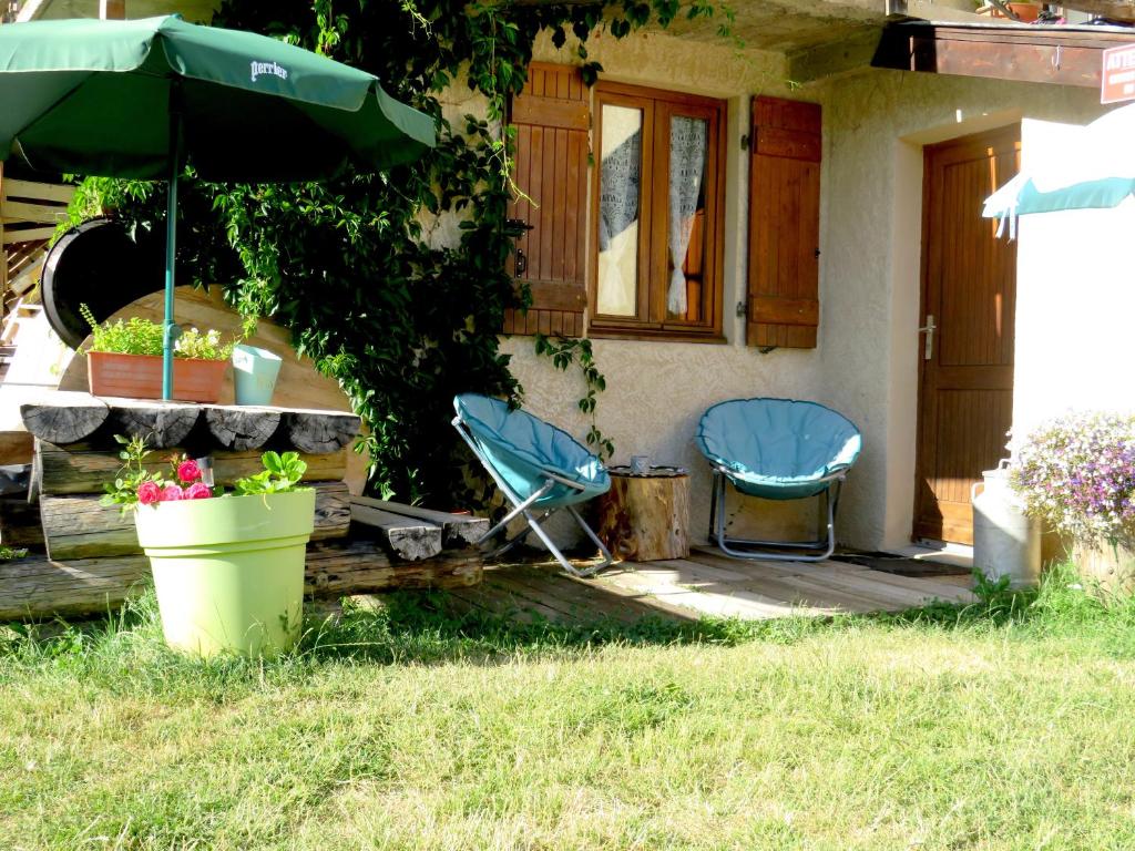 two chairs and an umbrella in front of a house at Studio en rez de chaussée, avec jardin partagé. in Vars