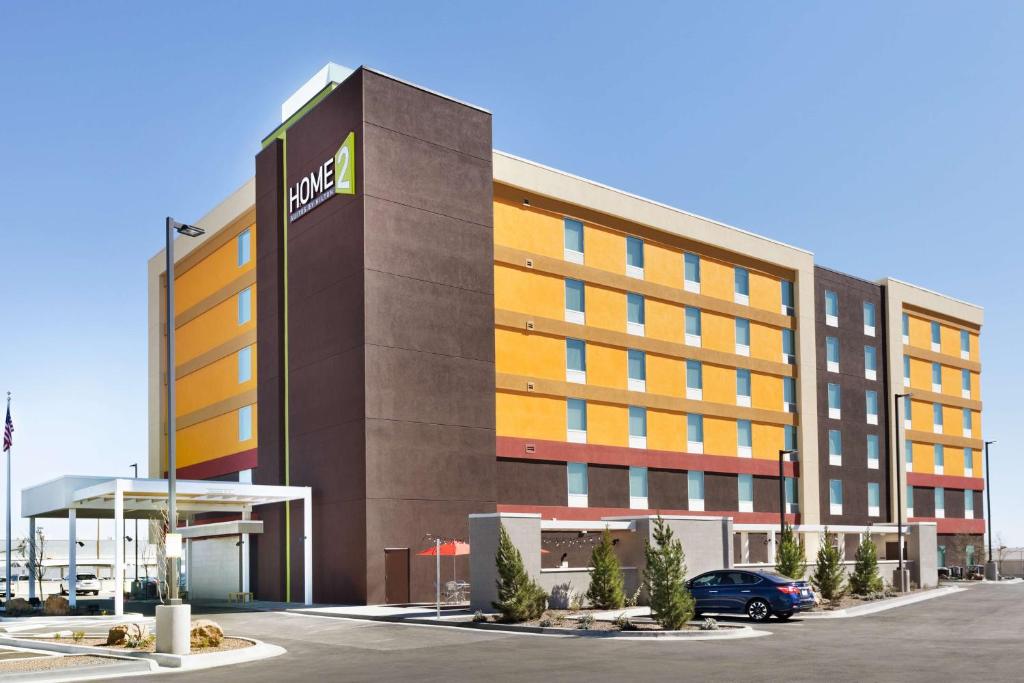 a hotel building with a car parked in a parking lot at Home2 Suites By Hilton El Paso Airport in El Paso
