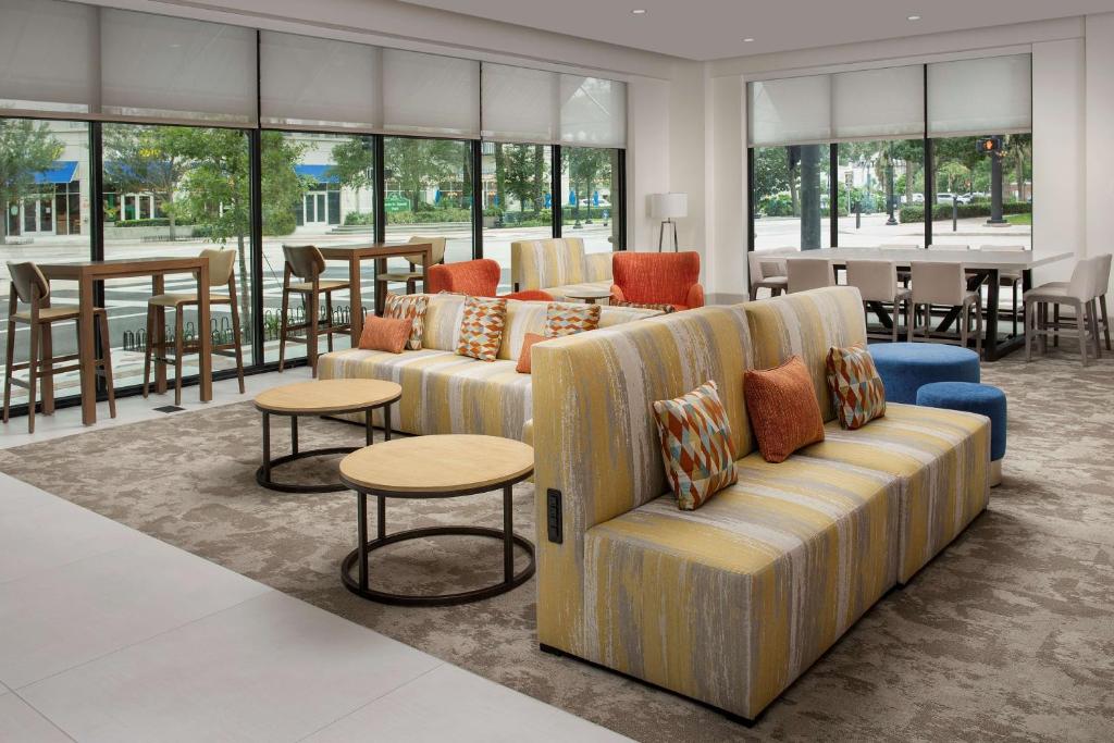 a living room with couches and tables and windows at Hilton Garden Inn Orlando Downtown in Orlando