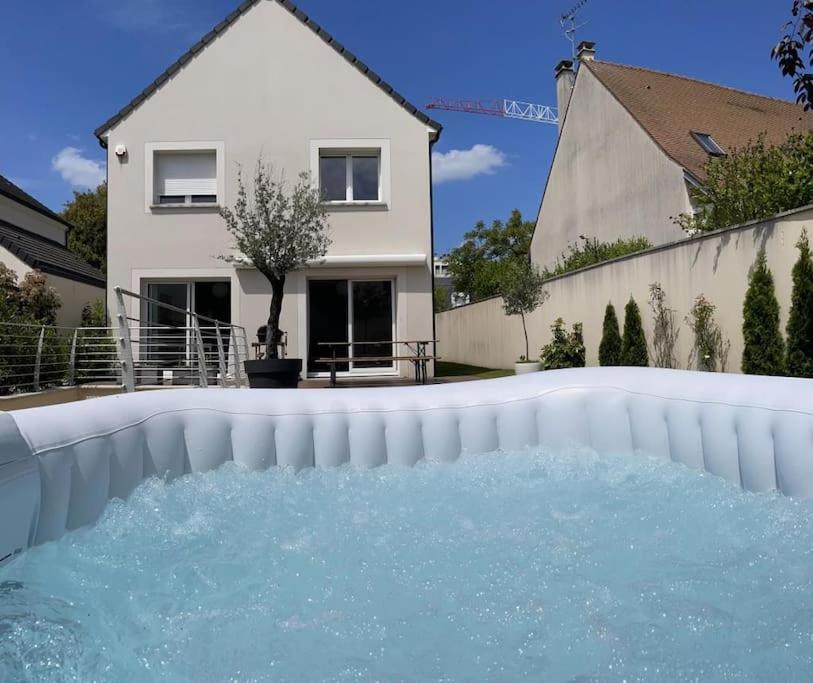 une piscine d'eau en face d'une maison dans l'établissement La villa des quais de Seine et jacuzzi prox Paris, à Sartrouville