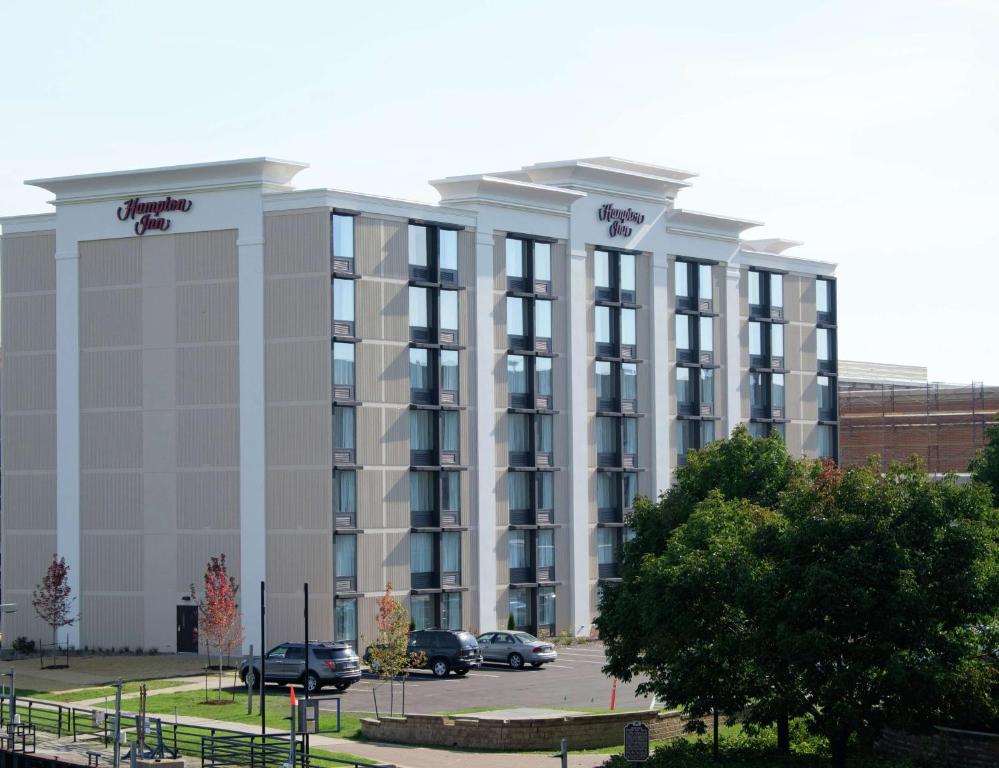 un gran edificio con coches estacionados en un estacionamiento en Hampton Inn Green Bay Downtown en Green Bay