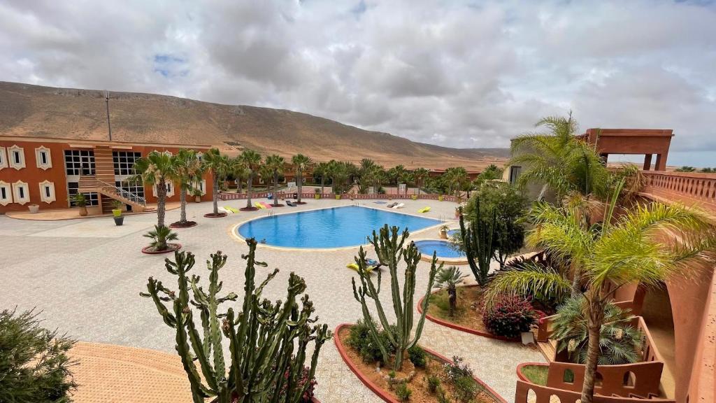 een resort met een zwembad en palmbomen bij Club Evasion in Tamelalt