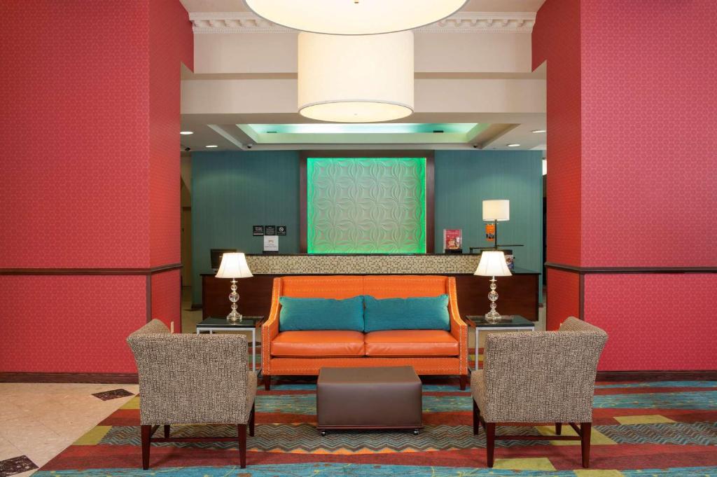 un sofá naranja en una habitación con 2 sillas en Hampton Inn Indianapolis Downtown Across from Circle Centre, en Indianápolis