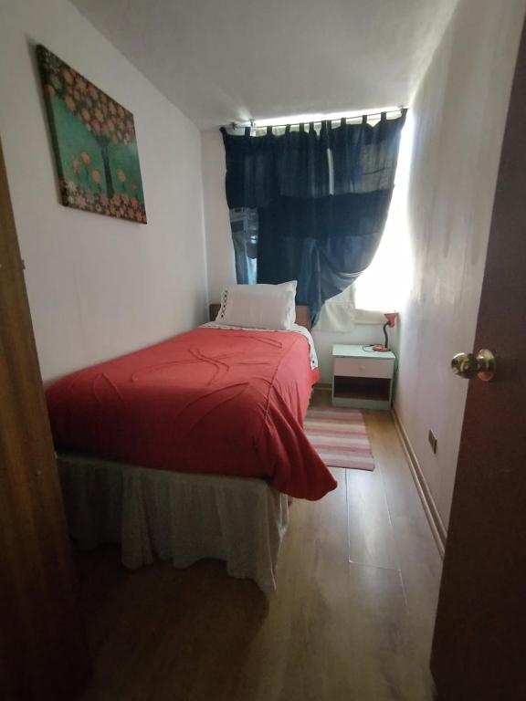 a small bedroom with a red bed with a window at Kingui in Santiago