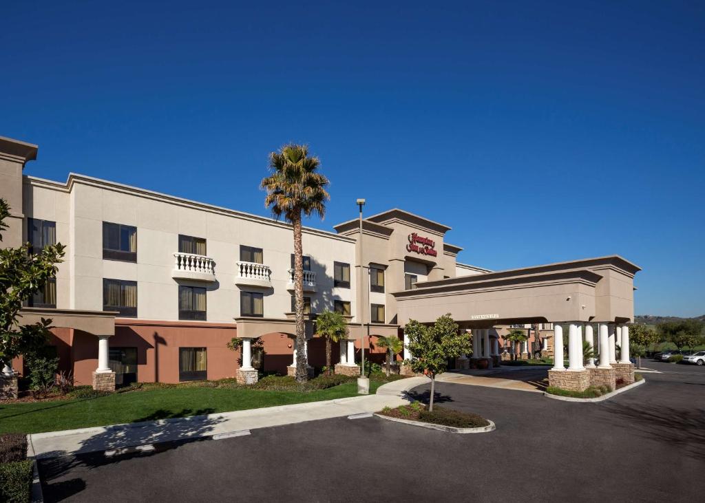 a hotel with a palm tree next to a parking lot at Hampton Inn & Suites Paso Robles in Paso Robles