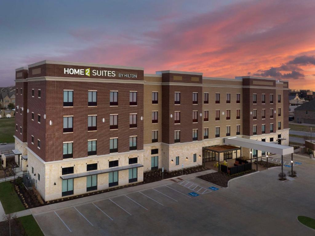 Flower MoundにあるHome2 Suites By Hilton Flower Mound Dallasの夕日を背景にしたホテルの描写