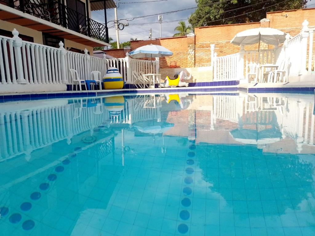 a swimming pool with blue water and white chairs at Hotel Gran Mansión de la Negra in Melgar