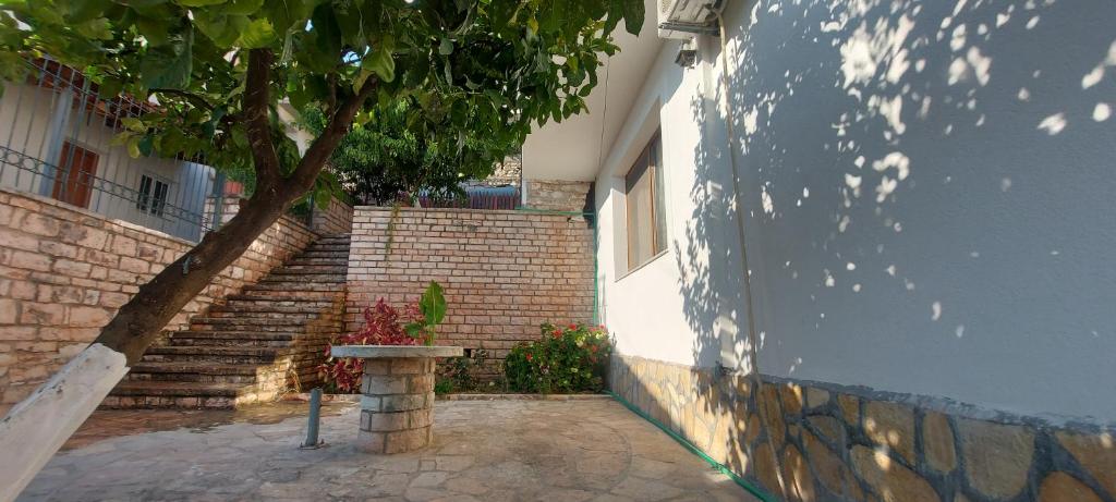 a tree sitting next to a brick building with a table at Duka Apartments Sarande in Sarandë