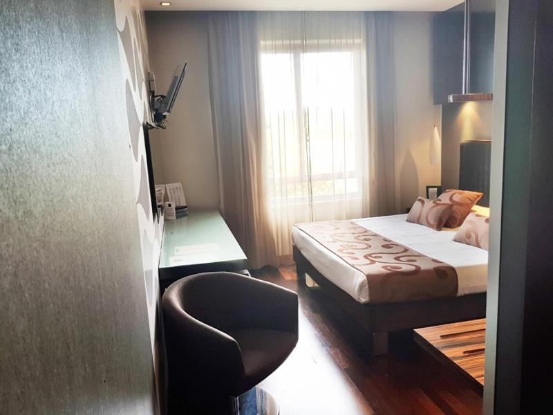 um quarto com uma cama, uma cadeira e uma janela em Axolute Comfort Hotel Como - Cantù em Cantù