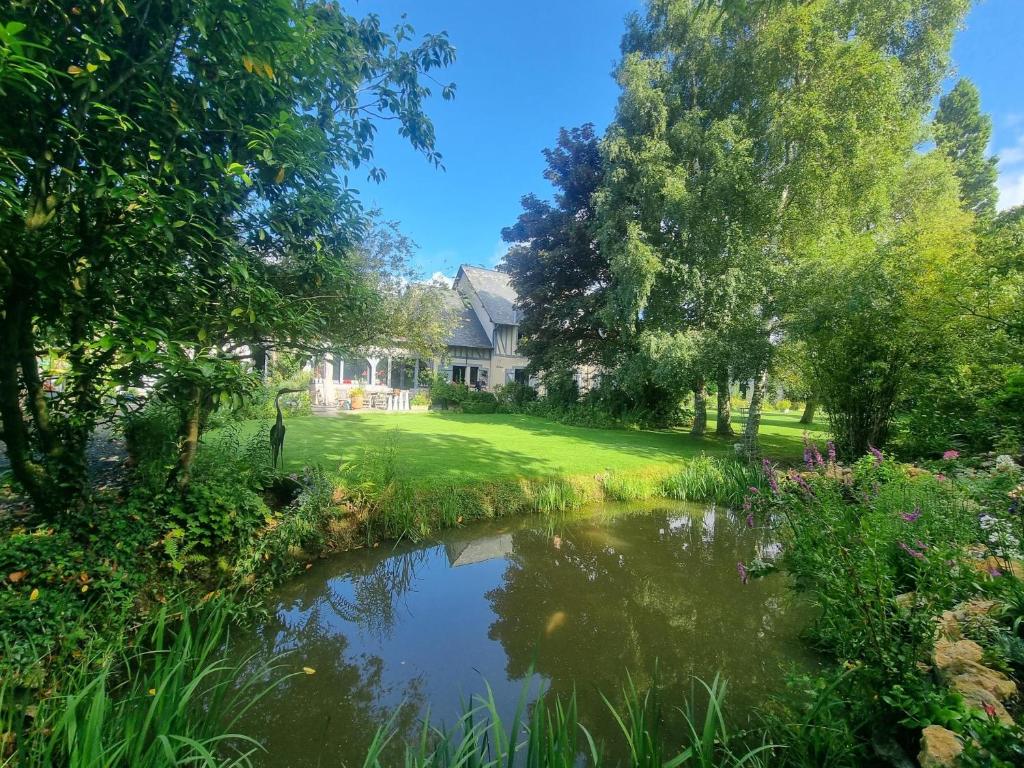 a house with a pond in front of a yard at Chambres et Table d'Hôtes du Coquerel in Saint-Siméon