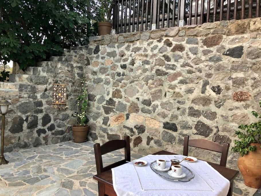 a table and two chairs and a stone wall at Kalliopi's House in Mandrakion