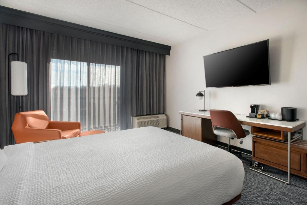 a hotel room with a bed and a desk and a television at Courtyard by Marriott Rye in Rye