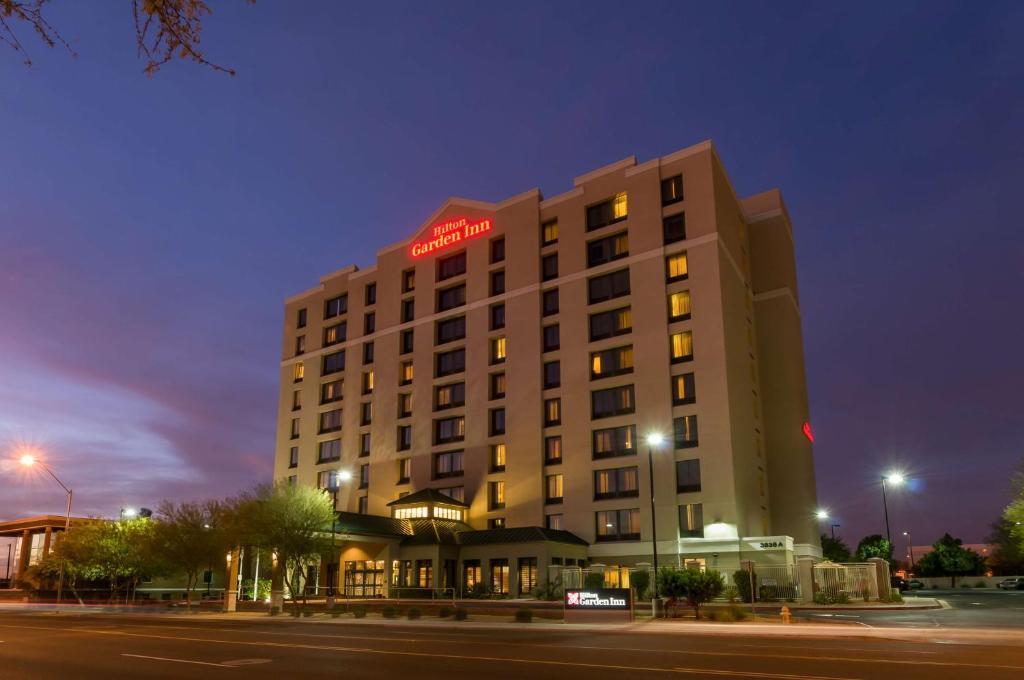 un edificio de hotel con un letrero de neón rojo. en Hilton Garden Inn Phoenix Airport North, en Phoenix