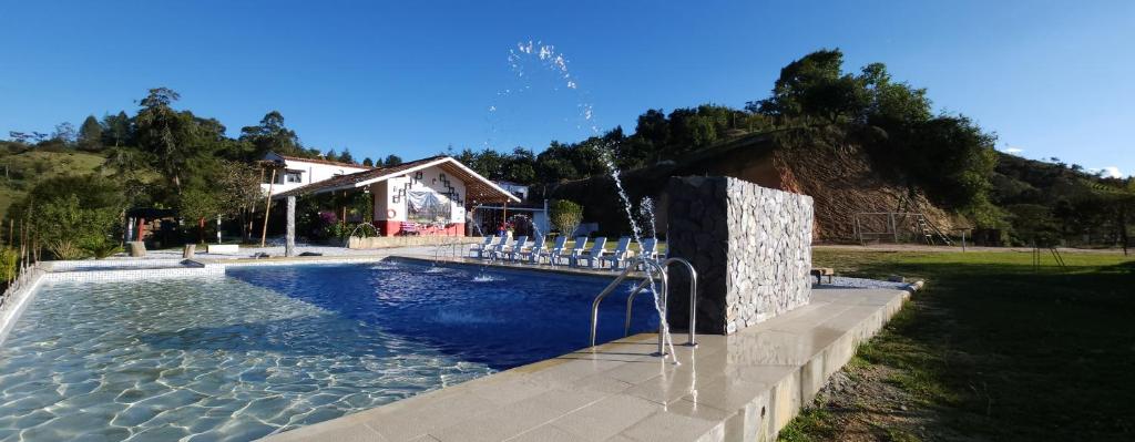 una piscina con sillas blancas junto a una casa en HOSTERÍA BRISAS DEL RÍO, en Marinilla