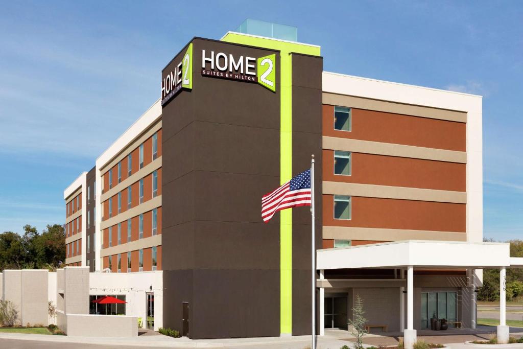 een hotelgebouw met een Amerikaanse vlag ervoor bij Home2 Suites by Hilton Stillwater in Stillwater