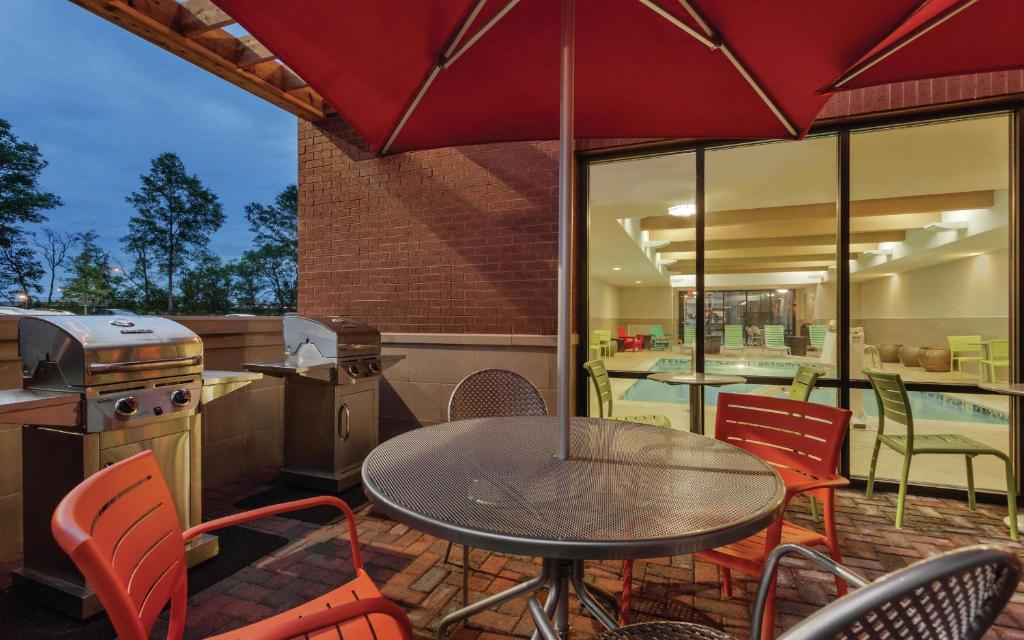 a patio with a table and chairs and a grill at Home2 Suites by Hilton Tuscaloosa Downtown University Boulevard in Tuscaloosa