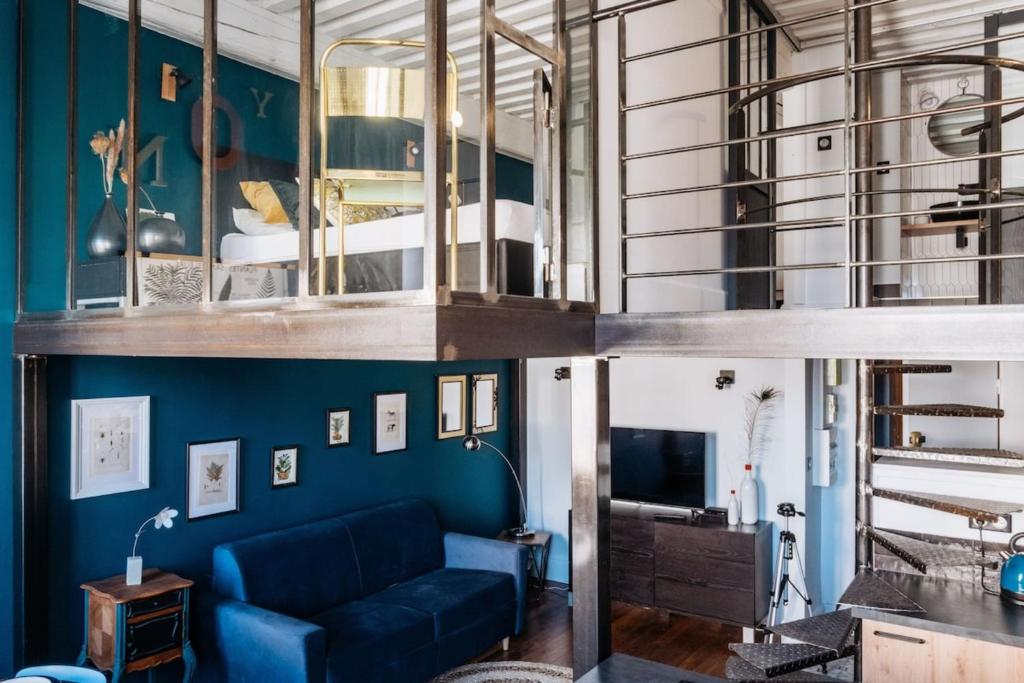 un salon avec un canapé bleu et une mezzanine dans l'établissement Perrod - Industrial Duplex Loft - Lyon Croix-Rousse, à Lyon