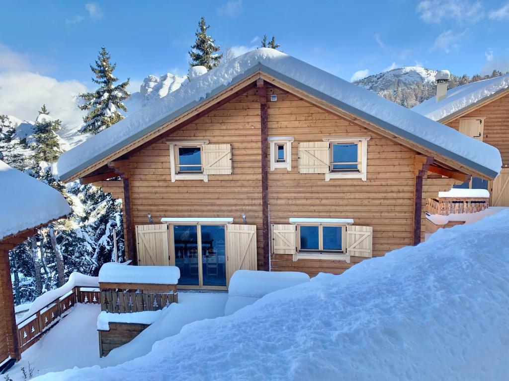 une maison en rondins dans la neige avec des terrains recouverts de neige dans l'établissement Oreeduloup Chalet Japp'loup 10/12 Pers., à Saint-Étienne-en-Dévoluy