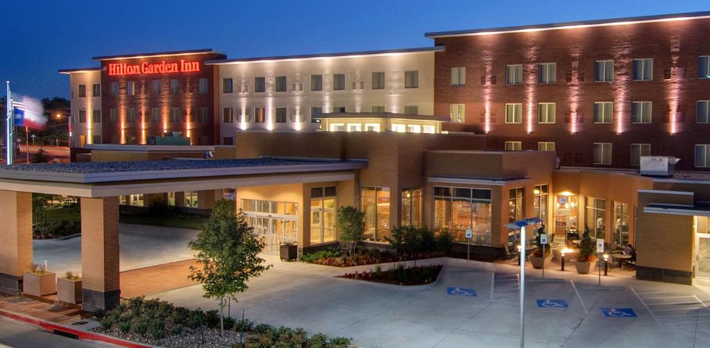 Hilton Garden Inn Fort Worth Medical Center في فورت وورث: مبنى الفندق وامامه ساحة فناء