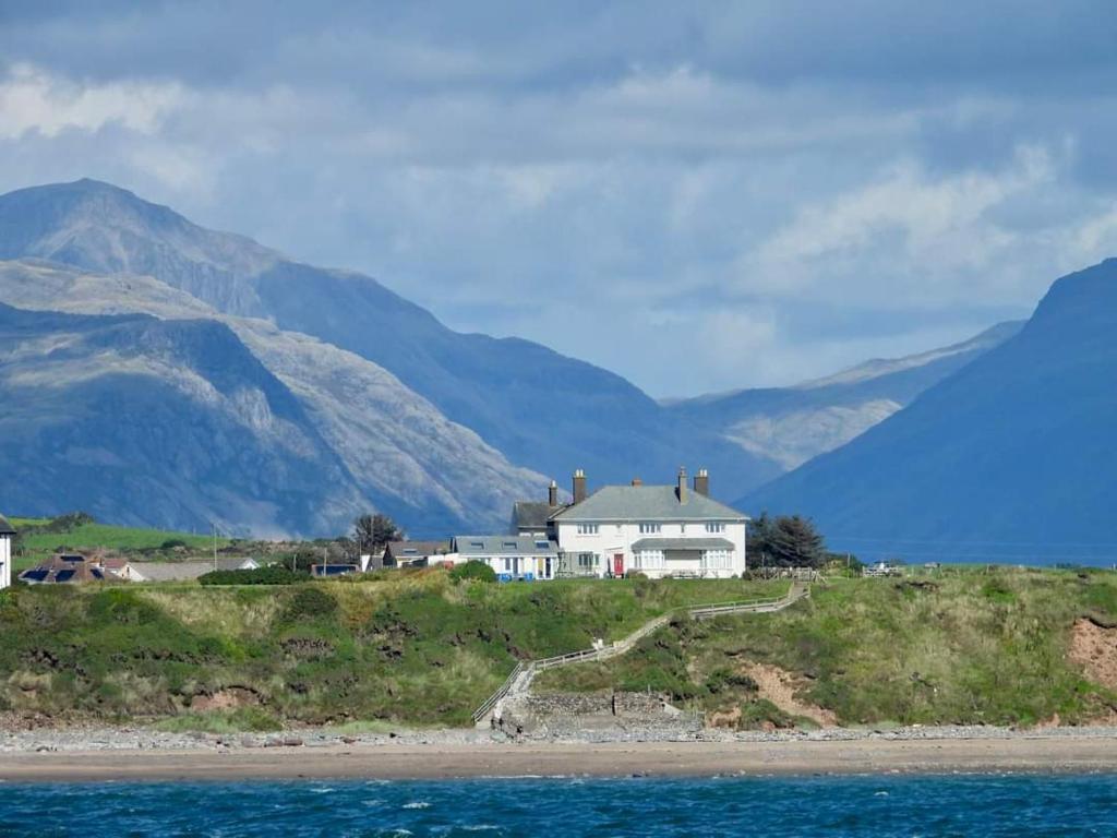 a white house on a hill with mountains in the background at Ideally located Cumbrian home with stunning views in Seascale