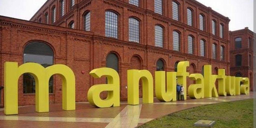 a large yellow sign in front of a brick building at Apartamenty blisko Manufaktury in Łódź
