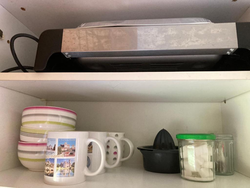 a shelf with a printer and plates and cups at F1 noir&#47;anis, avec terrasse couverte et jardin (E) in Compreignac