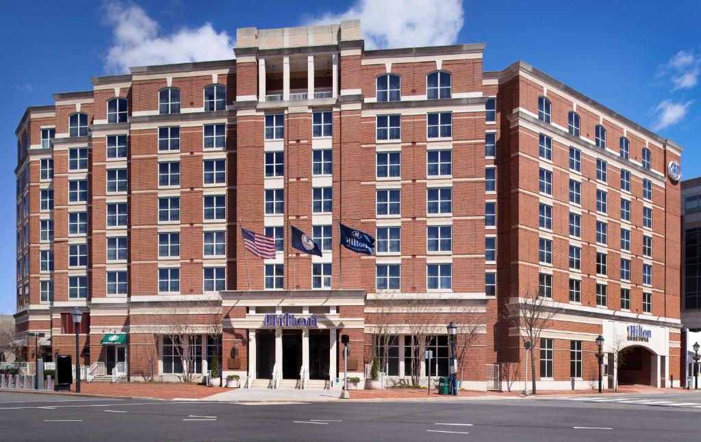 a large brick building with two american flags in front at Hilton Alexandria Old Town in Alexandria