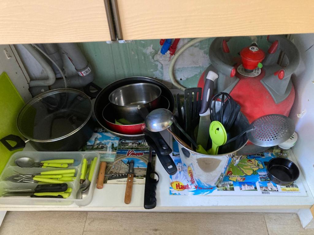 a shelf with a bunch of kitchen utensils at F1 noir&#47;anis, avec terrasse couverte et jardin (E) in Compreignac