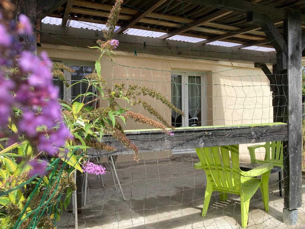a patio with two green chairs and flowers at F1 noir&#47;anis, avec terrasse couverte et jardin (E) in Compreignac