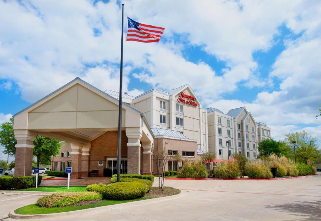 ein Hotel mit amerikanischer Flagge davor in der Unterkunft Hampton Inn & Suites N Ft Worth-Alliance Airport in Roanoke