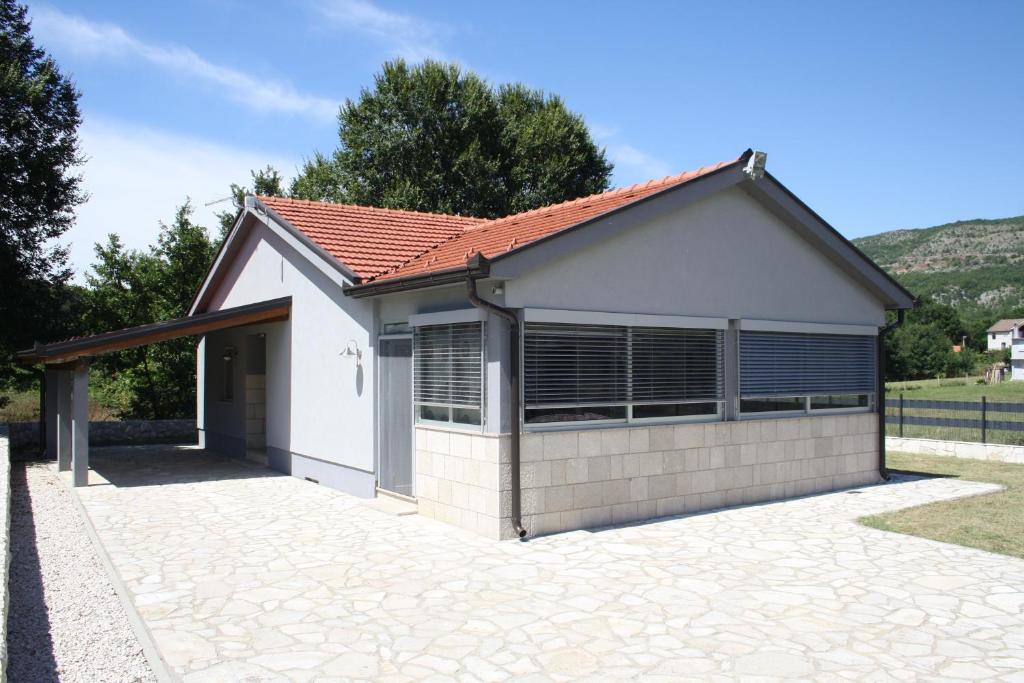 ein kleines weißes Haus mit Auffahrt in der Unterkunft KUĆA ZA ODMOR KIARA in Grude