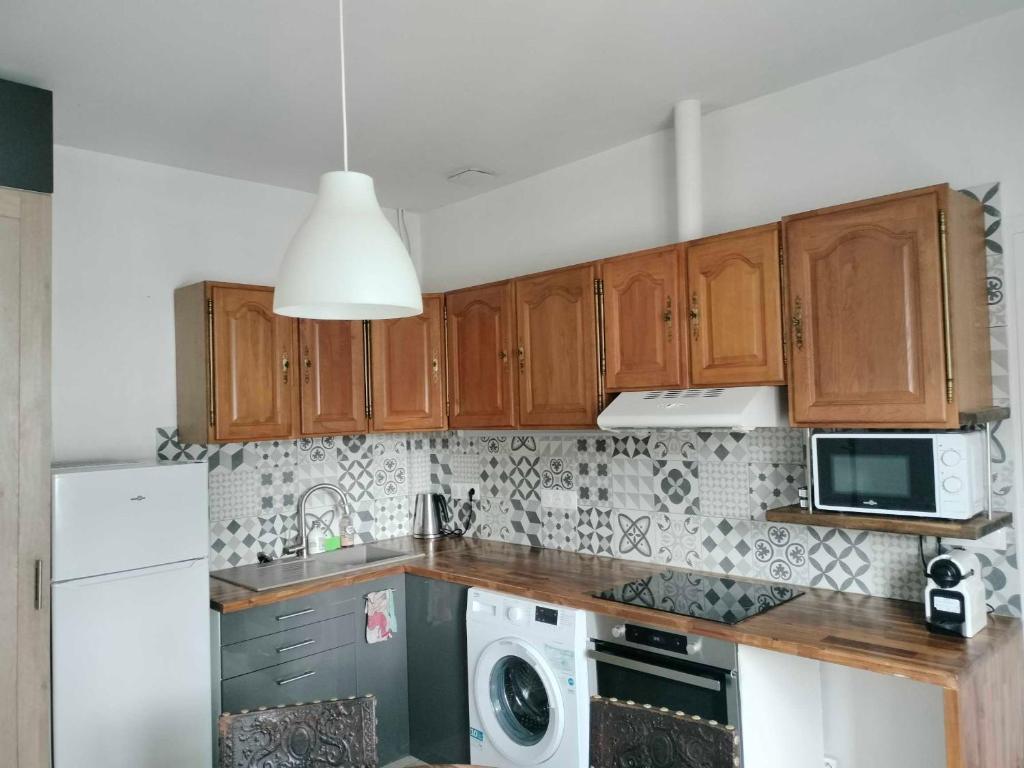 a kitchen with wooden cabinets and a washer and dryer at Appartement vintage in Vitry-sur-Seine