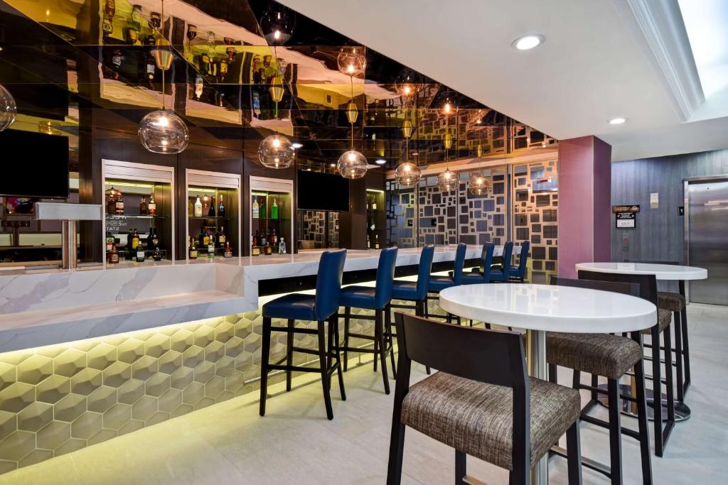 ein Restaurant mit einer Bar mit blauen Stühlen und Tischen in der Unterkunft Hampton Inn NY-JFK in Queens