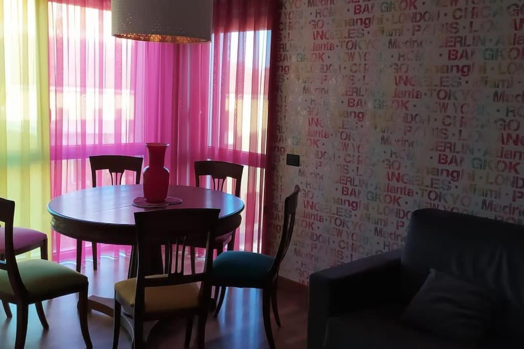 a dining room with a table and chairs and pink curtains at Appartamento di Anna in La Spezia