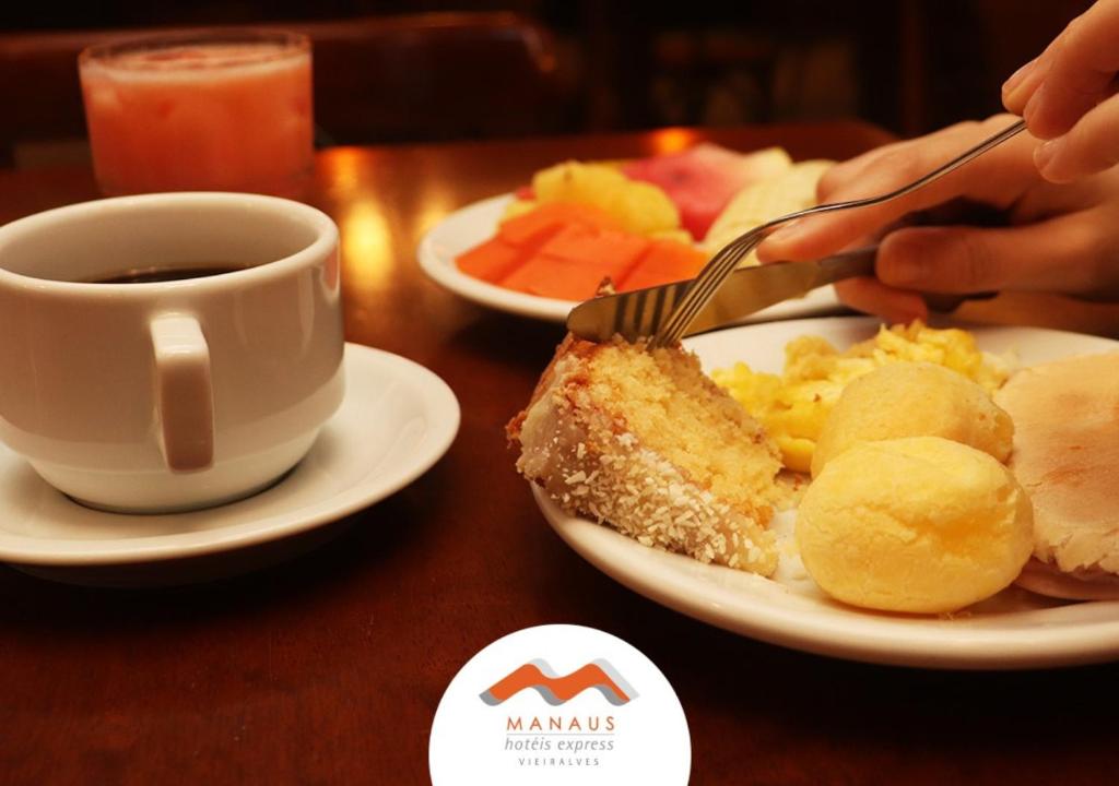 una mesa con un plato de comida y una taza de café en Express Vieiralves en Manaos