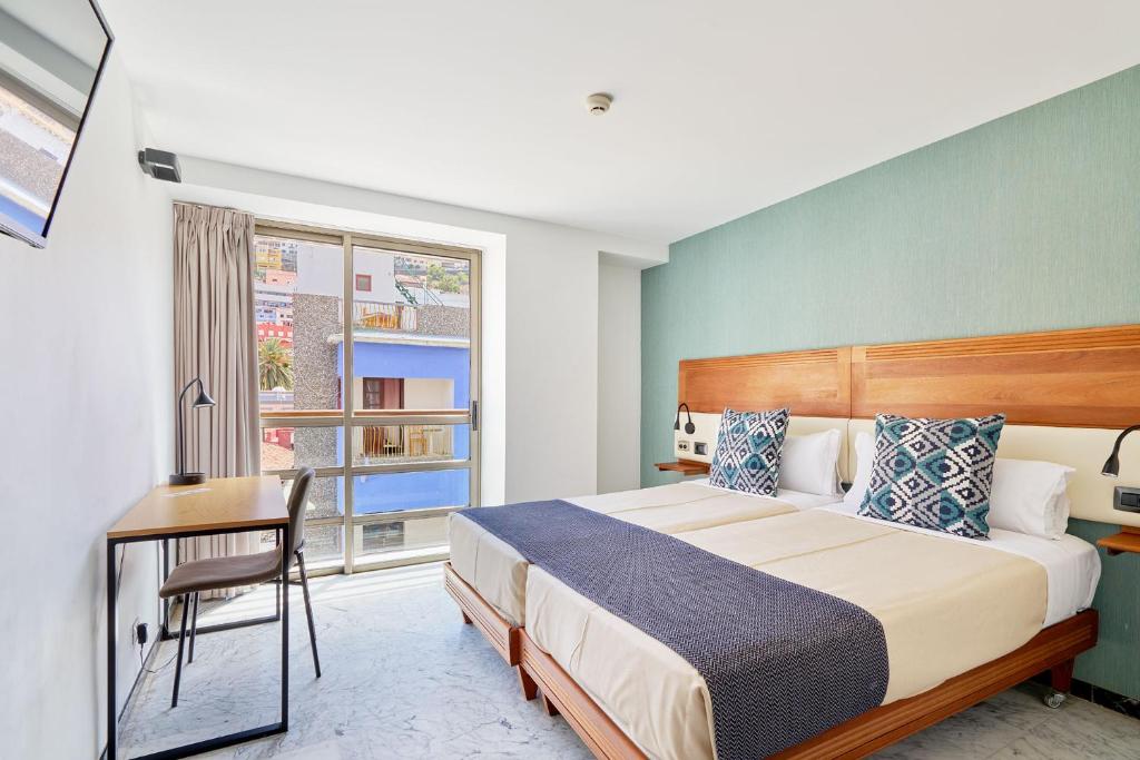 a bedroom with a bed and a desk and a window at Hotel Torre Del Conde in San Sebastián de la Gomera