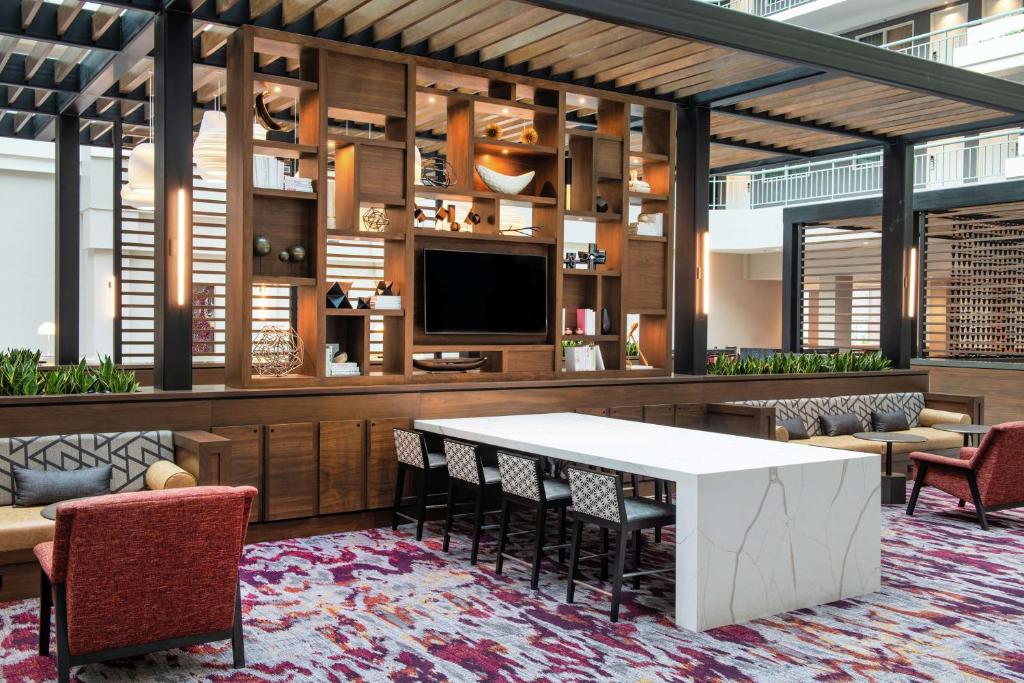 a lobby with a table and chairs and a tv at Embassy Suites by Hilton Walnut Creek in Walnut Creek