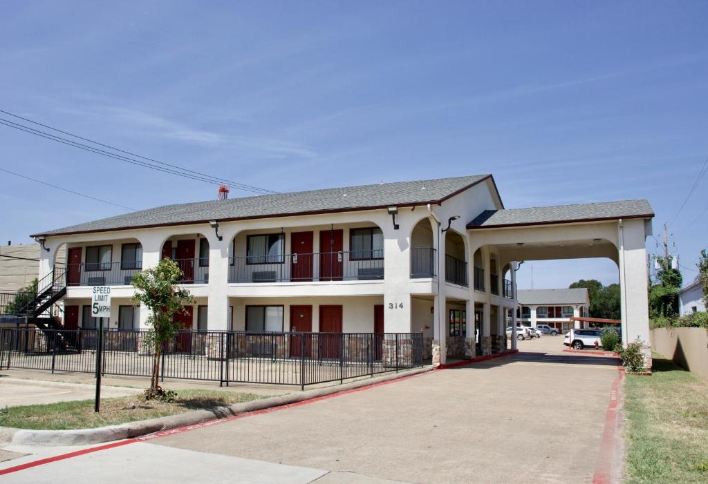 a white building with red doors and a gate at Executive Inn of Arlington, Near AT&T Stadium in Arlington