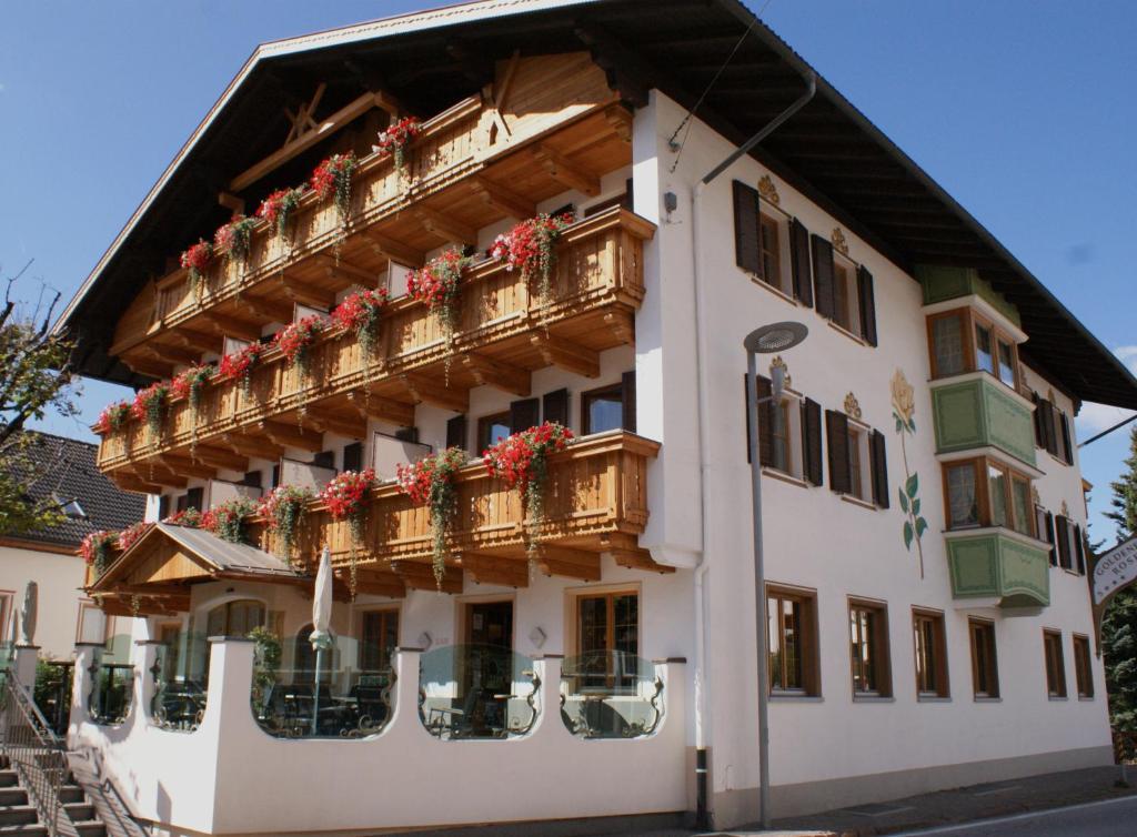 budynek z balkonami i czerwonymi kwiatami w obiekcie Hotel Goldene Rose w mieście Monguelfo