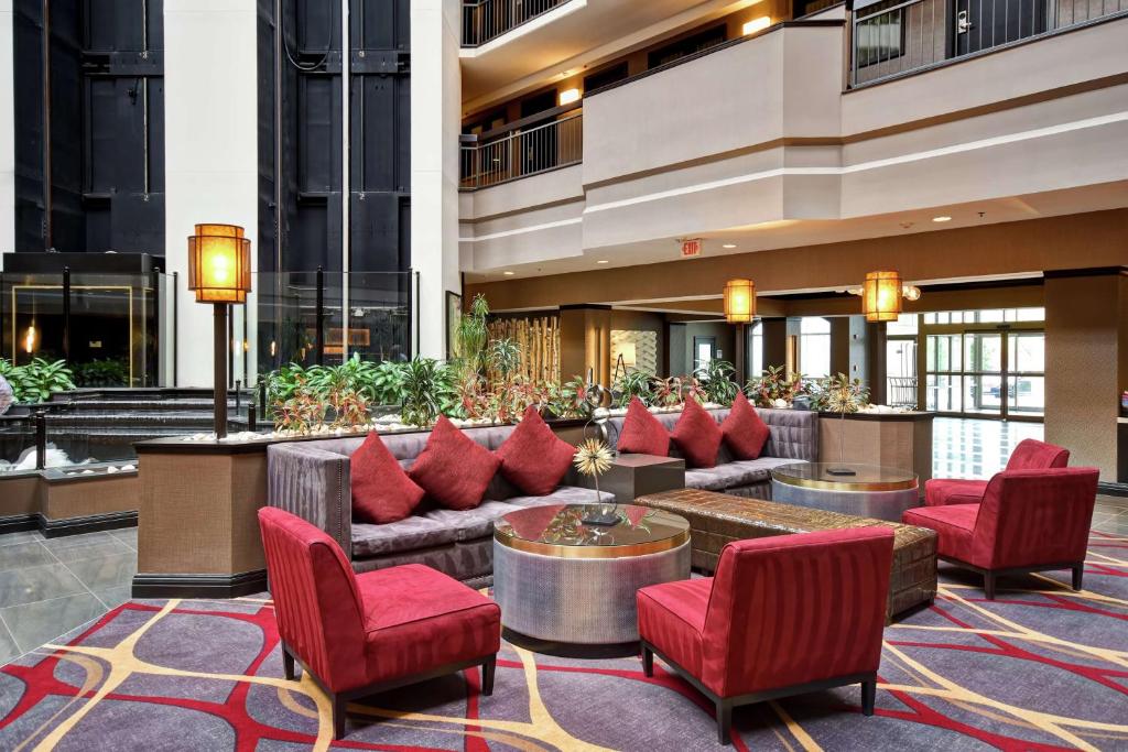 eine Lobby mit Sofas und roten Stühlen in einem Gebäude in der Unterkunft Embassy Suites by Hilton Dulles Airport in Herndon