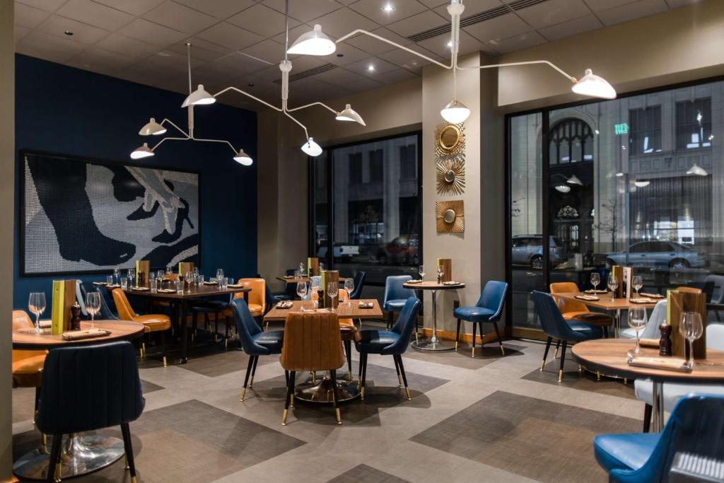 a dining room with tables and chairs and windows at the Curtis Denver - A DoubleTree by Hilton Hotel in Denver