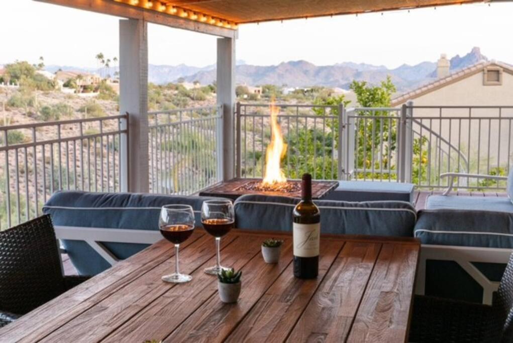 dois copos de vinho numa mesa de madeira com uma fogueira em Spacious home w/ Beautiful Views and Heated Pool em Fountain Hills
